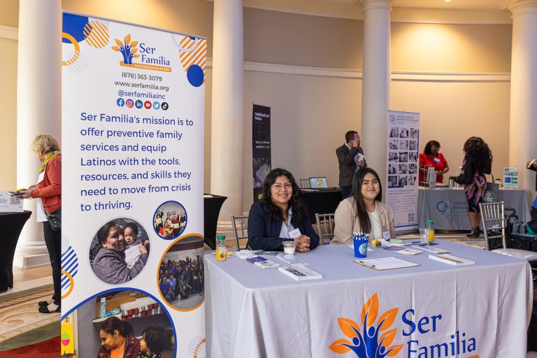 two women sitting at the Ser Familia vendor table